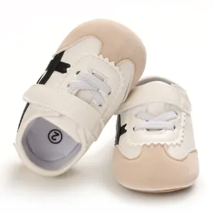 Detailed view of baby white soft-sole sneakers with beige suede and black stripes