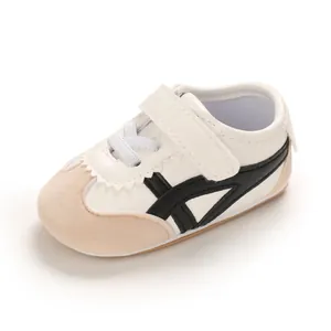 Detailed side view of white baby walking shoes with black stripes and velcro