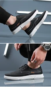 Close-up detail of men's black casual leather shoes with stylish orange stitching.