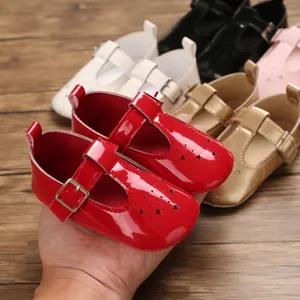 Nahaufnahme roter Baby-Mädchen-Sandalen aus Lackleder mit Sternen und T-Riemen-Schnalle.