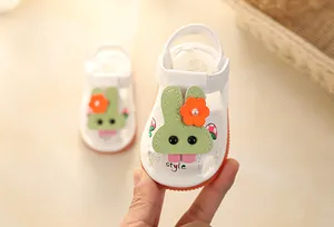 Detailed view of white baby summer sandals with cute cartoon bunny and soft orange sole