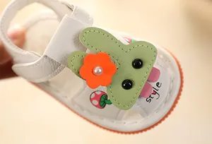 Macro detail of white baby sandal featuring a cute green rabbit and orange flower patch