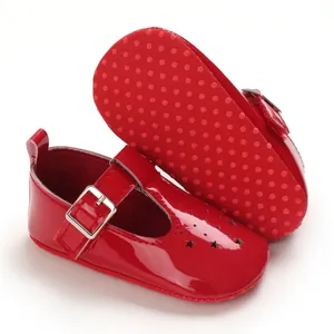 Nahaufnahme von roten Lackleder-Babyschuhen für Mädchen mit ausgestanzten Sternmustern.