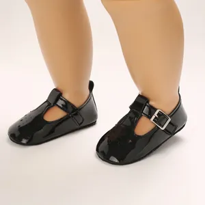 Nahaufnahme von schwarzen Baby-Lacklederschuhen mit Stern-Ausschnitten und T-Riemchen-Verschluss.