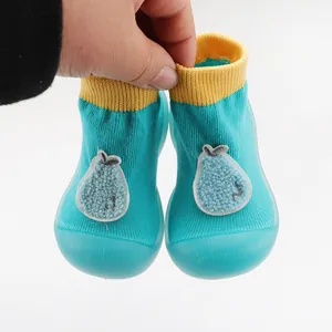 Close-up of turquoise baby socks shoes with pear patch and soft rubber soles.