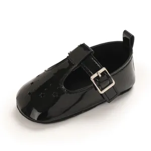 Detail eines schwarzen Lacklederschuhs für Babys mit Sternenperforation und Schnalle.
