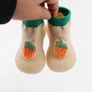 Close-up detail of baby walker sock shoes featuring a cute carrot applique and soft rubber sole