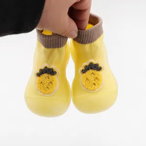 Detail of yellow baby sock shoes with cute fruit patch and soft translucent sole
