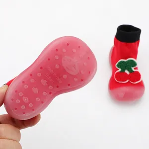 Close-up of pink translucent soft rubber sole for red baby walker sock shoes with cherry design