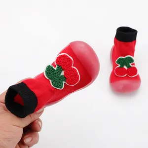 Close-up of red baby sock shoes with textured cherry applique and soft flexible rubber sole.