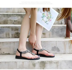 Stylish bohemian flat sandals featuring rhinestone flower T-strap design worn on model