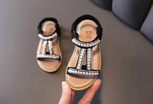 Close-up detail of girls' black Roman sandals with elegant pearls and rhinestones.