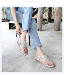 Lifestyle view of silver Bohemian sandals with rhinestone flower detailing on feet.
