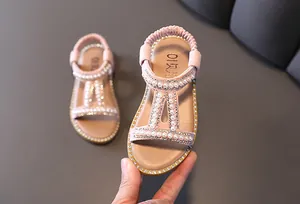 Close-up of pink girls' Roman sandals featuring elegant pearls and shiny rhinestones.