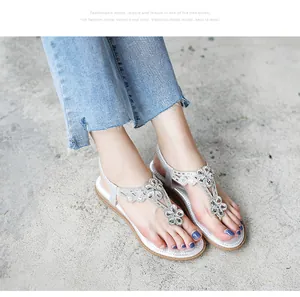 Close-up of silver bohemian thong sandals with intricate rhinestone flower details.