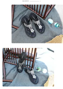Close-up of black bohemian sandals with rhinestone flower details and T-strap design