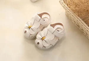 Close-up of white baby girl sandals with cute bunny bow and soft non-slip soles