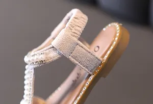 Detailed macro view showing faux pearl and sparkling rhinestone accents on girl's sandals