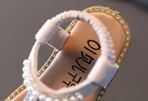 Close-up detail of elegant girls princess sandals featuring pearls and rhinestone trim