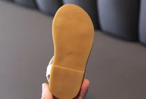 Close-up of the non-slip rubber sole on a girl's sandal featuring size 21 embossing