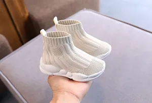 Primo piano di sneakers alte in maglia color crema per bambini con spesse suole bianche.