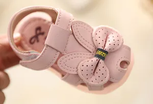 Detailed view of pink baby girl sandals featuring a cute rabbit ear bow and soft sole.