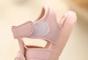 Macro detail showing the soft pink leather and secure velcro strap on baby girl sandals