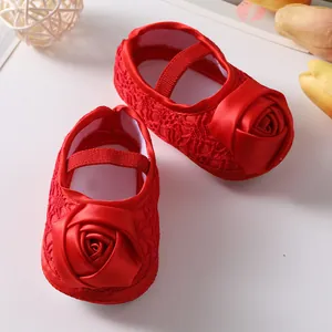 Macrodetail van rode baby prinsessenschoenen met satijnen roos en fijn kant