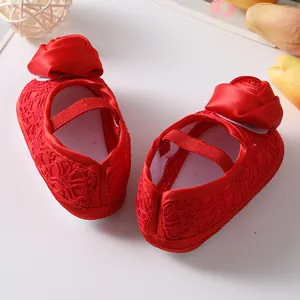 Gedetailleerd zicht op rode baby prinsessenschoenen met een grote zijden roos decor