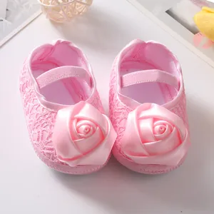 Detailopname van roze baby prinsessenschoenen met grote satijnen roos en kant