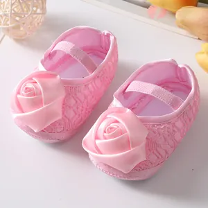 Detailopname van roze kanten baby prinsessenschoentjes met grote satijnen roos decor