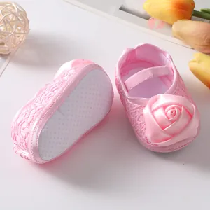 Detailopname van roze baby prinsessenschoenen met een zijden roos en een antislipzool.