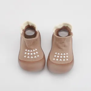Primer plano de zapatos calcetín transpirables marrones para bebé con suela blanda.