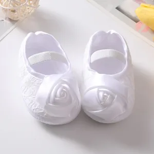 Detailopname van witte baby prinsessenschoentjes met satijnen roos en kanten accenten