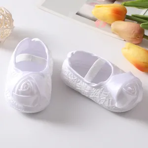 Detailweergave van witte baby prinsessenschoenen met kant en een grote satijnen roos.
