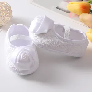 Detailweergave van elegante witte babyprinsessenschoenen met roos en kanten patroon