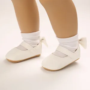 Detailaufnahme weißer Baby-Prinzessinenschuhe mit einer eleganten Schleife an der Ferse