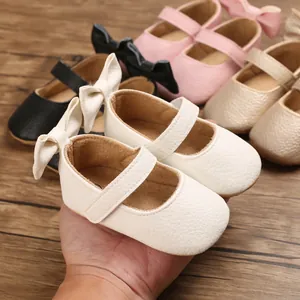 Nahaufnahme von eleganten weißen Lauflernschuhen mit weicher Sohle und großer Zierschleife