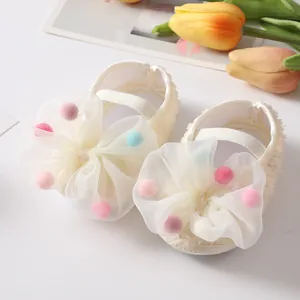Close-up of baby girl princess shoes with large tulle bow and colorful pom-poms