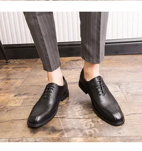 Detailed view of black men's leather business dress shoes worn on a wooden floor