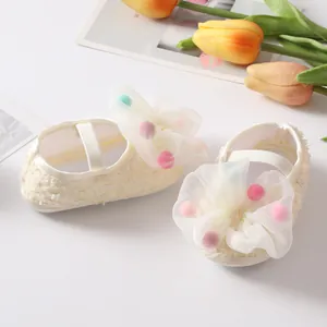 Detailed view of cream baby princess shoes with tulle bows and colorful pom-poms