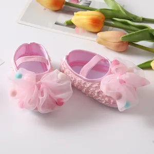Close-up detail of cute pink baby princess shoes featuring mesh bows and colorful pom-poms