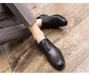 High-angle view of men's black pointed-toe leather dress shoes styled with grey striped pants