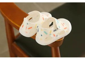 Close-up view of white toddler sandals featuring colorful pill prints and mesh design