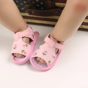 Gros plan de sandales roses pour bébé avec broderie florale et semelle souple