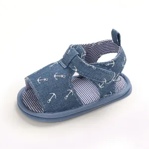 Vue latérale d'une sandale pour bébé en jean bleu avec motifs d'ancres blanches et doublure rayée