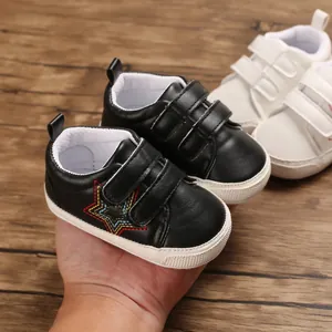 Gros plan de chaussures de marche noires pour bébé avec étoile brodée et double velcro