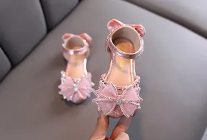 Vue détaillée d'une sandale de princesse rose avec un nœud en strass étincelant et sequins.