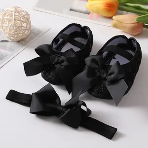 Detail view of black lace baby princess shoes with matching oversized bow headband.