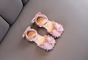 Gros plan de sandales de princesse roses pour filles avec nœuds en strass brillants.